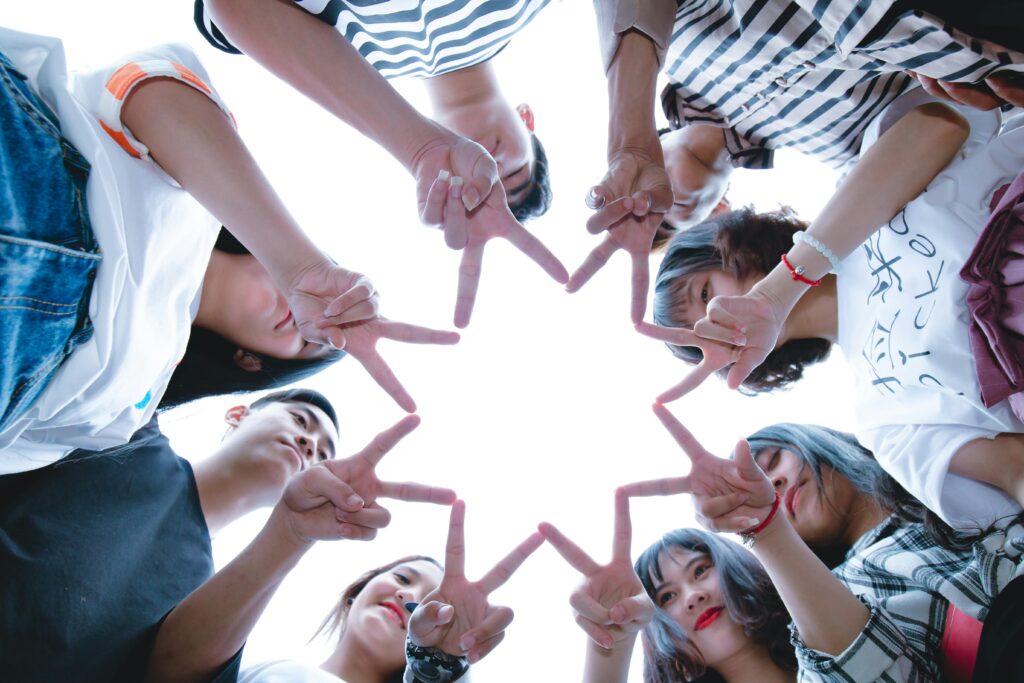 A circle of friends forming a star shape with fingers, symbolizing unity and teamwork.