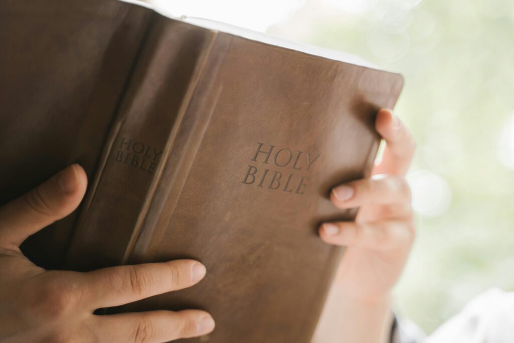 Hands gently holding a Holy Bible in natural lighting, evoking spiritual reflection.